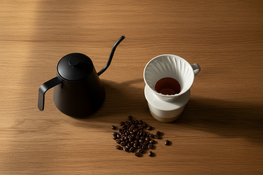 Pour over coffee starter kit flat lay with V60 dripper, gooseneck kettle, and ceramic mug on wood surface