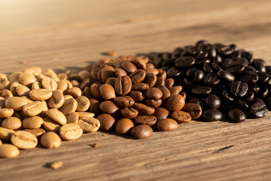 Three coffee roast levels side by side — light, medium, and dark roast beans on a wooden surface